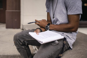 man sitting holding a notepad and writting